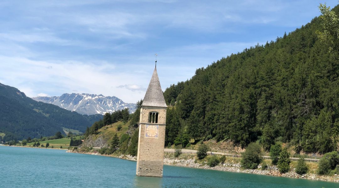 Der Kirchturm des versunkenen Dorfes Grauen ragt aus dem aufgestauten Reschensee.